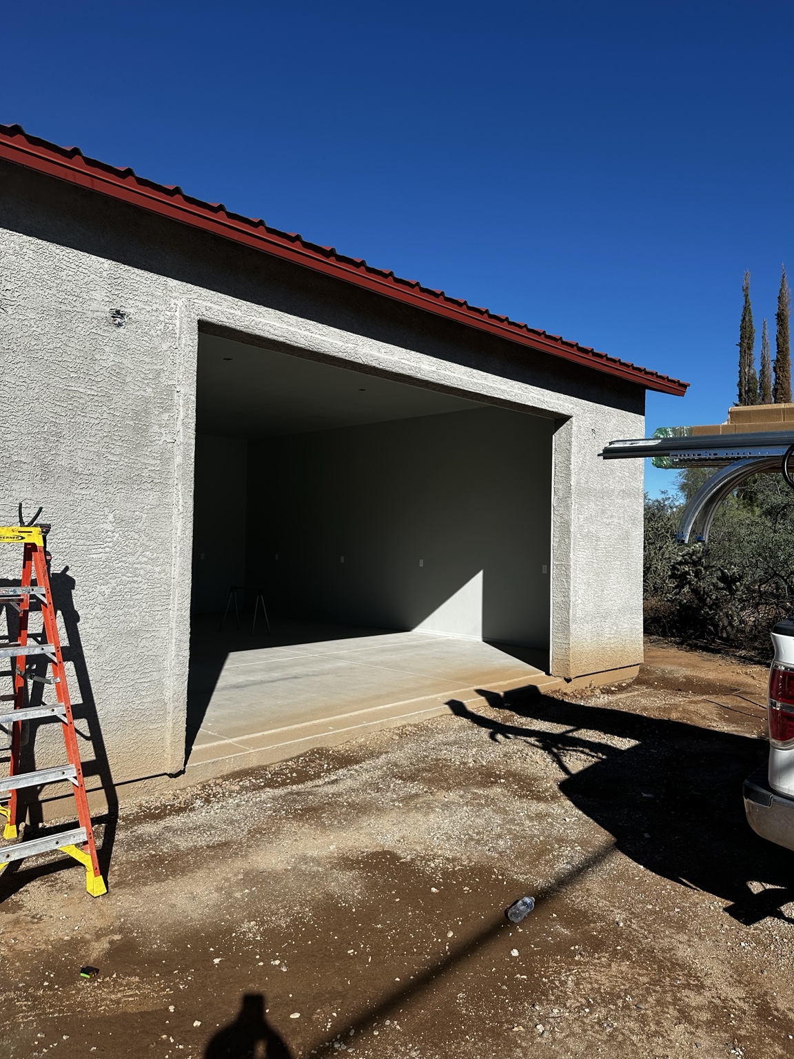Open garage opening before door installation, with a ladder beside it.